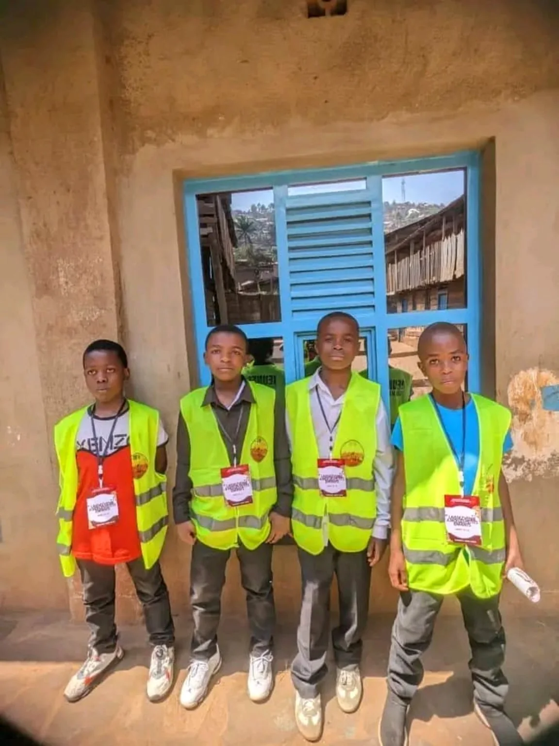 Quatre jeunes portant les gilets de Circle of Future devant une école