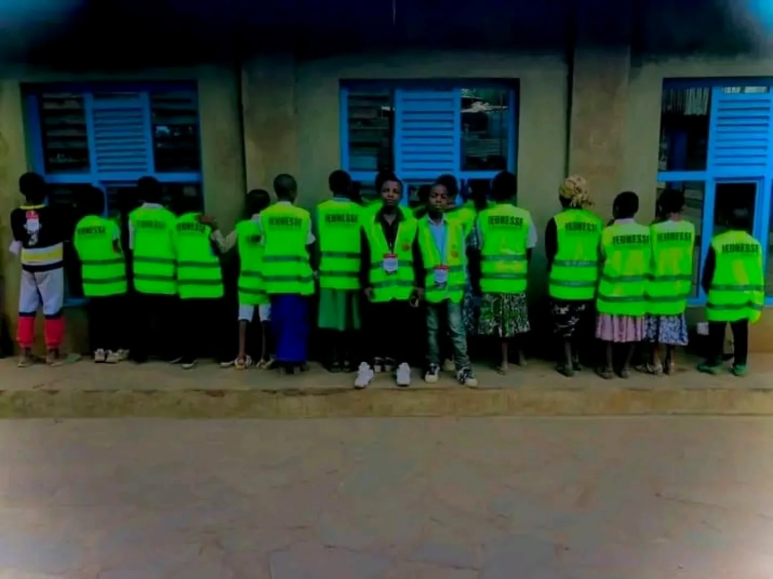 Groupe de jeunes en gilets verts devant une école